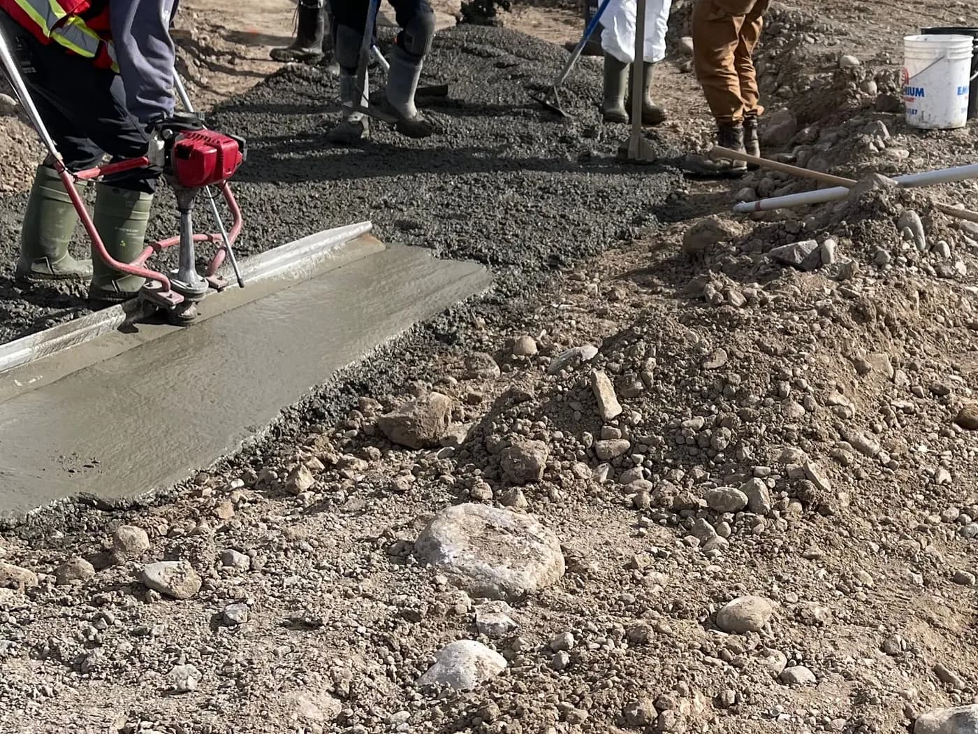 Crew finishing a fresh concrete pour with a power screed on a community construction site