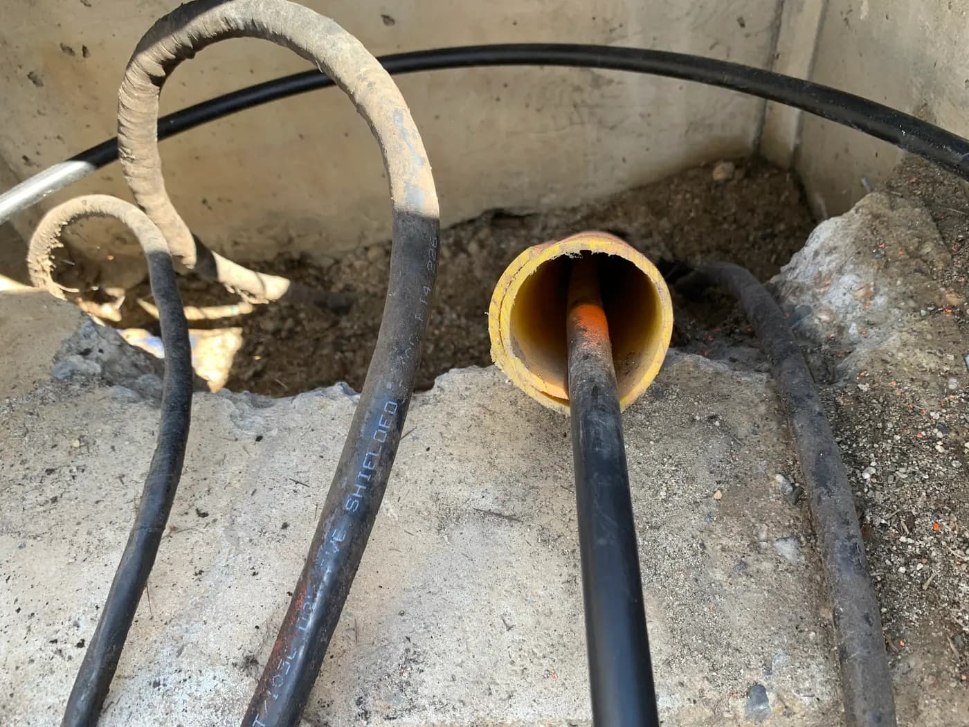 Electrical cables pulled through underground conduit into a concrete utility vault