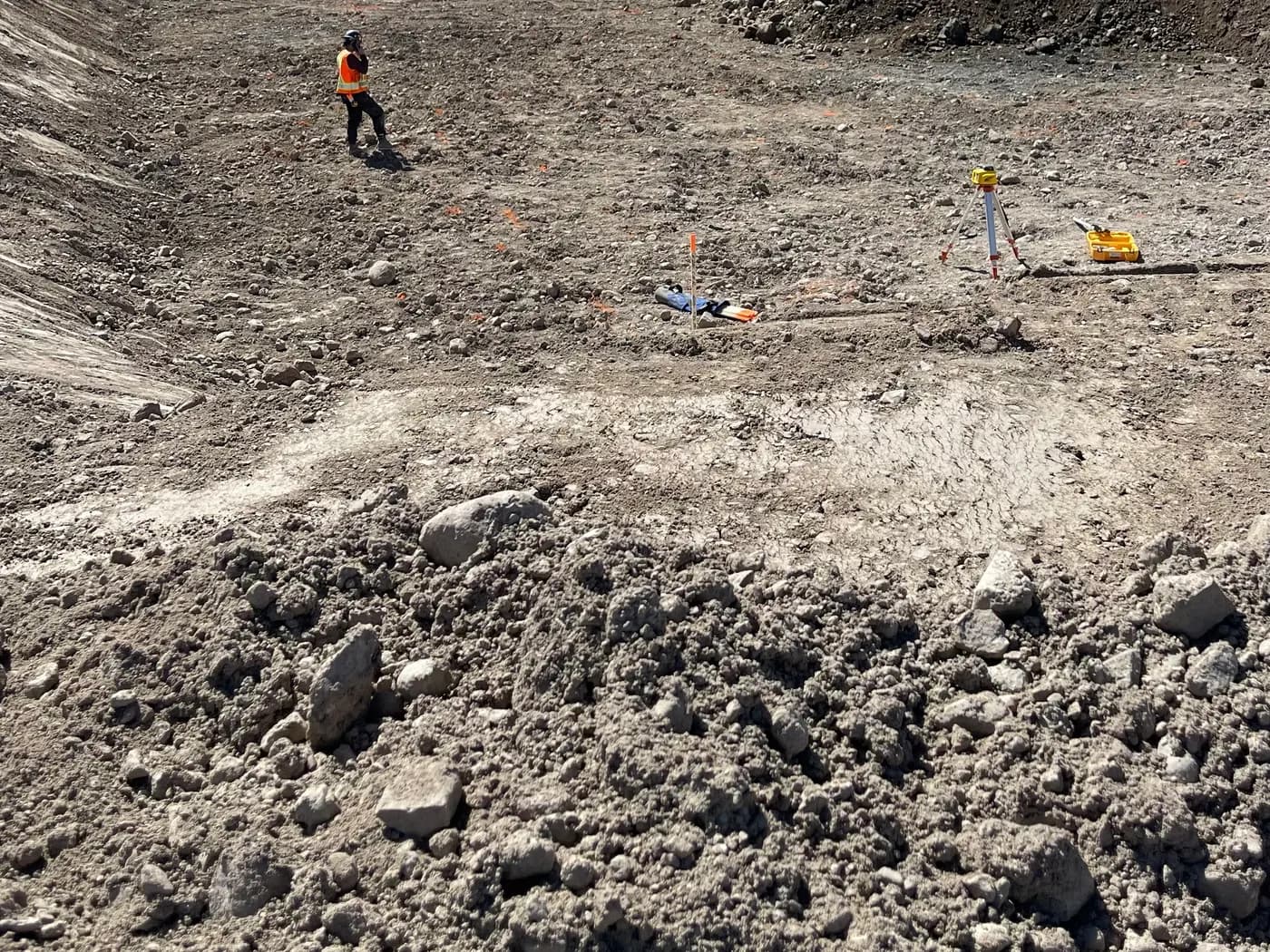 Site stripped to native ground during clearing and grubbing, with a crew member checking grades