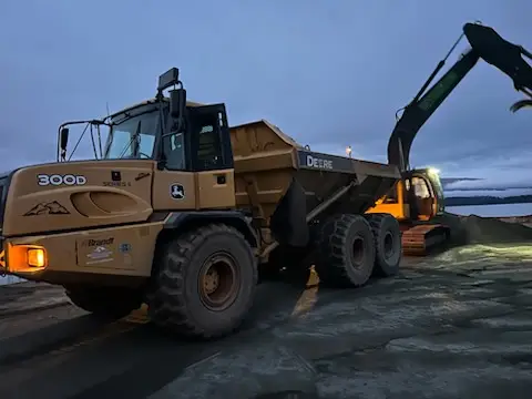 Excavator loading an articulated rock truck with structural fill