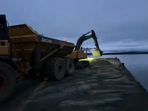 Rock truck and excavator placing material on a shoreline jetty on the BC coast
