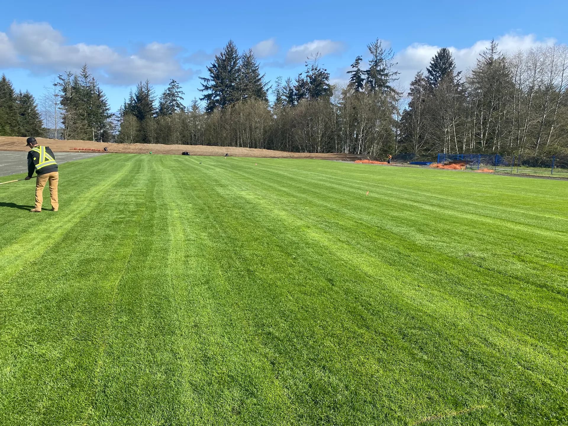 Crew installing big-roll sod on a new community sports field