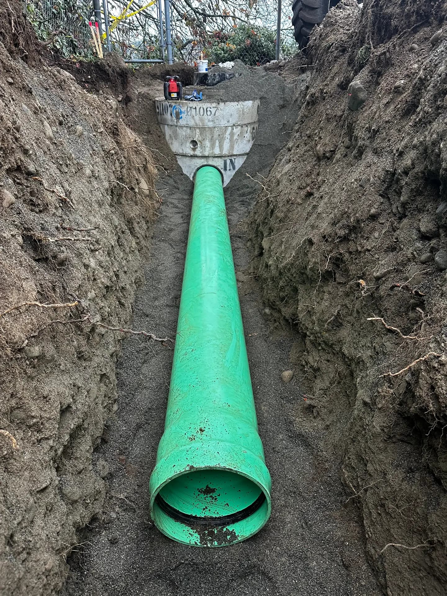 New green PVC storm sewer main installed and bedded in an open trench